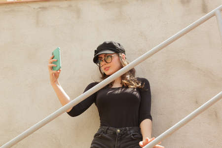 Stylish woman taking a selfie in the city near a guardrailの写真素材