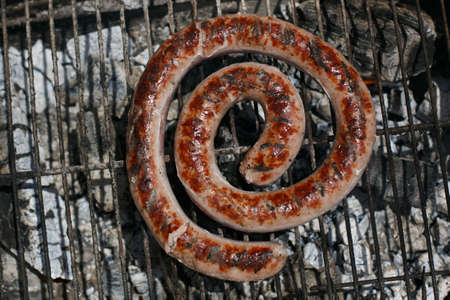 Fresh sausage cooking on the barbecue, in the open airの写真素材