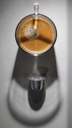 Coffee cup with shadow projected on a white tableの写真素材