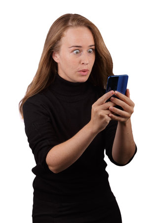 Young blonde girl smiling with mobile phone in hand with white background.の写真素材
