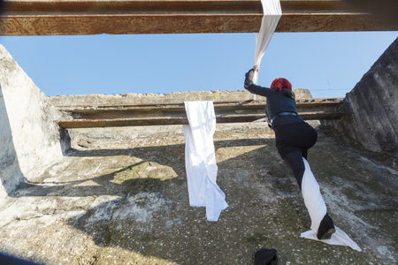 woman with fabrics climbing a train track structure to climb to the top