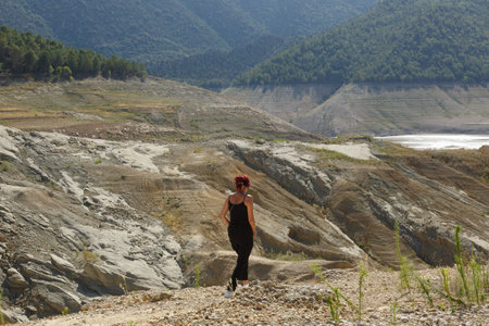 A woman is venturing through a rugged terrain surrounded by breathtaking mountain vistas