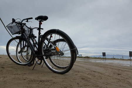Various bicycles can be seen placed on the sandy beach with a wonderfully cloudy sky high above