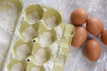 A carton of eggs is positioned right next to several brown eggs, indicating a variety of egg types...