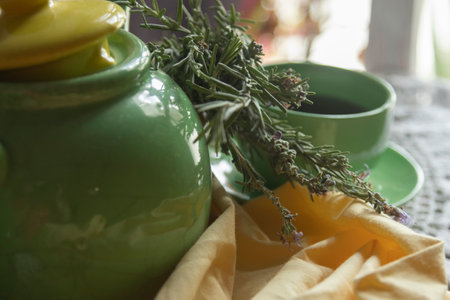 A charming rustic tea setup that features a lovely green pot, a cute cup, and an array of fresh herbsの写真素材