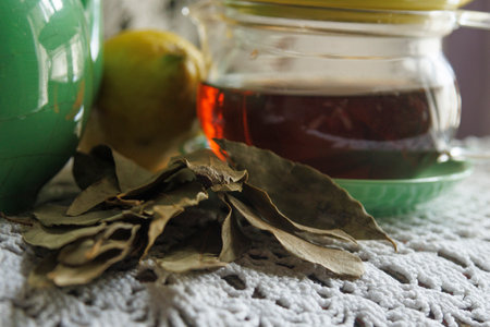 A lovely composition of dried colorful leaves and herbal tea in a glass jar placed on a beautifully textured surfaceの写真素材