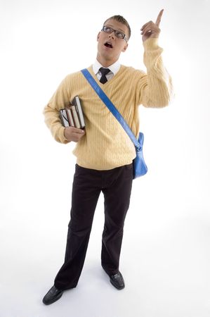 young student carrying bag and books pointing upwards on an isolated white backgroundの写真素材