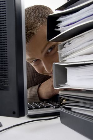 young man looking between files and computer on an isolated background