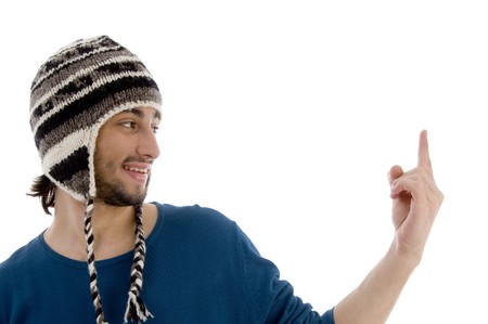 young man in woolen cap pointing upwards on an isolated white background