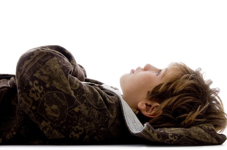 side view of little kid resting on floor against white backgroundの写真素材