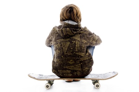 back pose of boy sitting on skateboard with white backgroundの写真素材