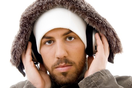 close up of serious male listening to music in headphone against white background