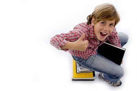 top view of boy sitting on pile of books on an isolated white backgroundの写真素材