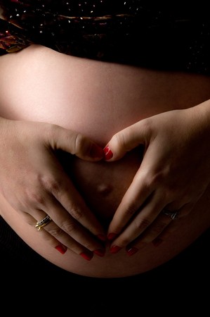 front view of pregnant female's tummy with her hands on an isolated backgroundの写真素材