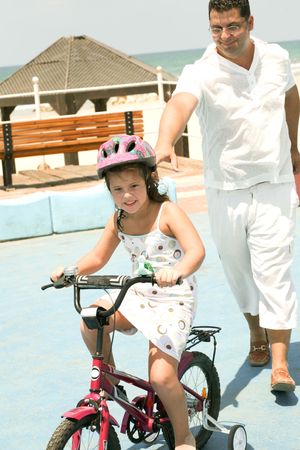 Young man helping kid learn bike ridingの写真素材