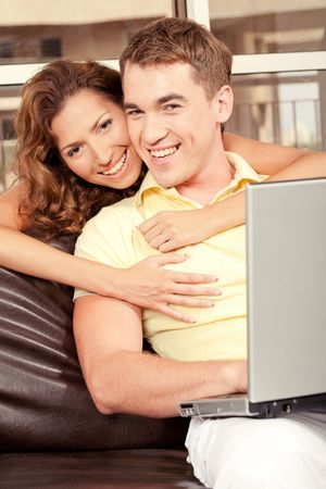 Young woman embracing her man from behind and smilingの写真素材