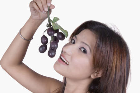 Portrait of a young woman holding fruit near her mouthの写真素材