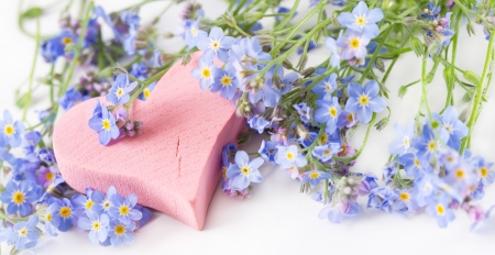 Pink wooden heart among wildflowers の写真素材