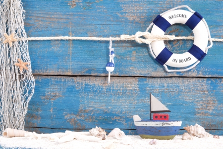 Lifebuoy and toy boat with shells on a wooden blue backgroundの写真素材