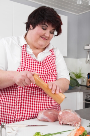 Overweight woman preparing ham - cooking at home の写真素材