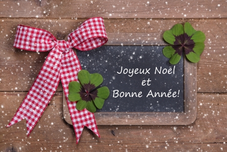 Chalk board with Merry Christmas message , santa and snowflakes on wooden in french with a red checkered ribbon with textの写真素材