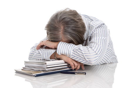 Grey haired woman sleeping on books - overworked isolated on white background - burn outの写真素材