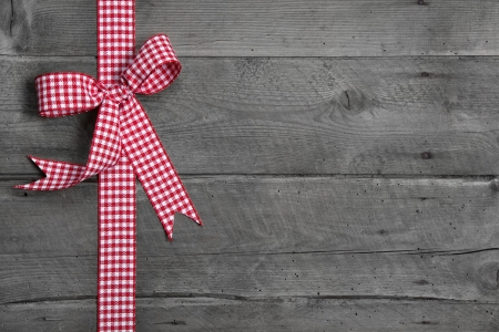 Grey wooden background with red and white checkered bow as border - idea for a festive rustic advertising boardの写真素材