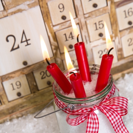 Christmas eve: four red burning candles with a shabby white advent calendar background - classic decoration in country style with woodの写真素材