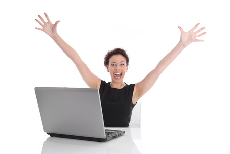 Ecstatic pretty woman sitting at desk with laptop and stretched out arms  isolated on white background の写真素材