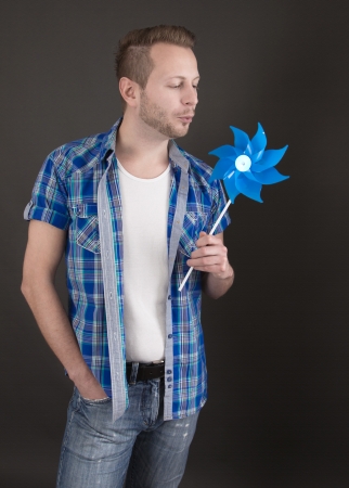 Dreamy young man in blue with pinwheelの写真素材