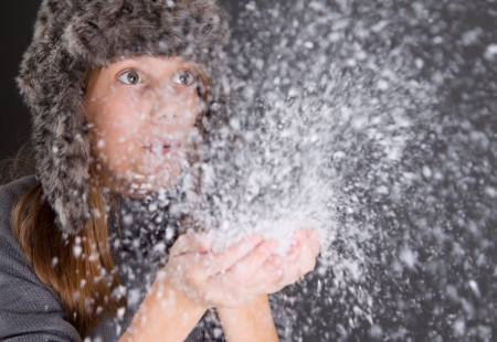 At last winter - girl blowing snow from handsの写真素材