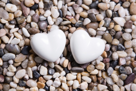 Two white hearts on a pebble stone background.の写真素材