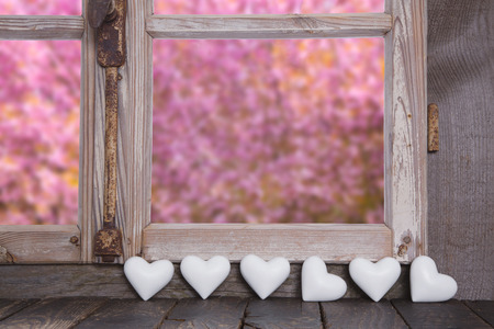 Summertime: wooden window with garden view and white hearts