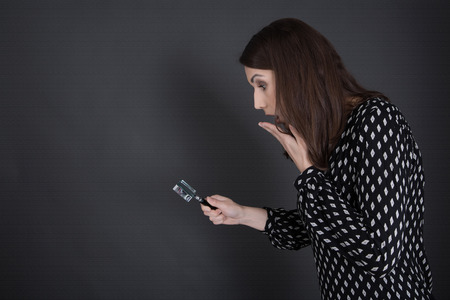 Business woman in black searching terms and conditions with magnifying glass isolated on blackboard.