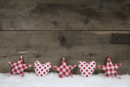 Wooden christmas background with red white checked hearts and stars on snow の写真素材