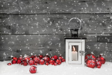 White shabby chic latern for christmas with candle and red balls on a grey wooden background.の写真素材
