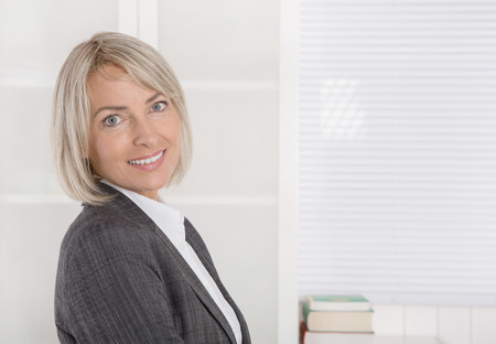 Attractive smiling senior business woman in portrait wearing blazer and blouse.