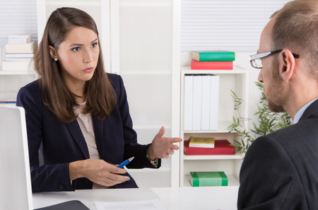 Customer and smiling female financial agent in a discussion at desk.の写真素材