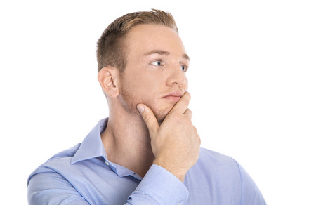 Pensive and unhappy isolated young blond businessman in blue shirt looking sideways to text.の写真素材