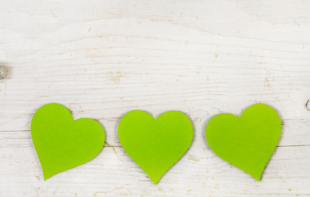 Three apple green hearts on old white shabby style wooden background.の写真素材