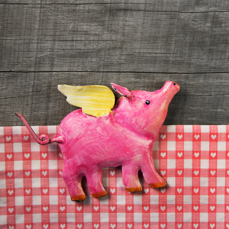 Flying happy pink pig on wooden old checked background. Symbol for happiness and luck.の写真素材