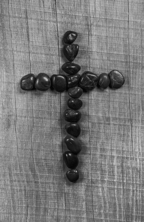 Black cross of stone on wooden grey background.の写真素材