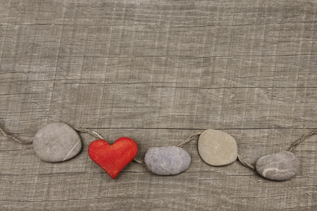 One red heart with stones on wooden background. Greeting card for lovers, friendship or valentineの写真素材