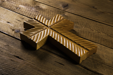 Old antique cross on wooden background for mourning or death concepts.の写真素材