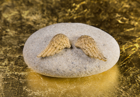 Stone with golden angel wings: greeting card for die, death, communion or baptism.の写真素材