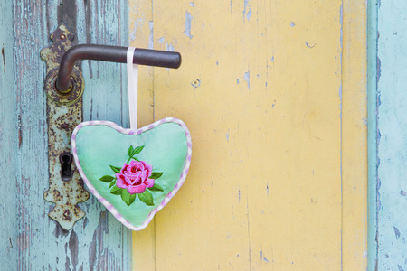 Handmade fabric heart hanging on an old door handle.の写真素材