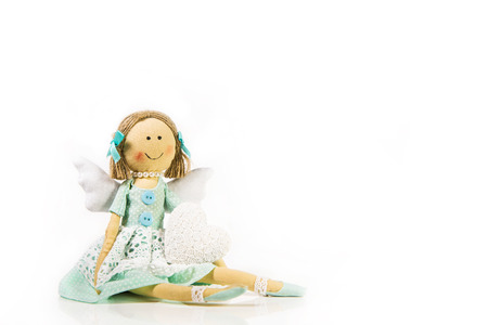 Guardian angel: isolated handmade doll or puppet with a white heart in her hands.の写真素材