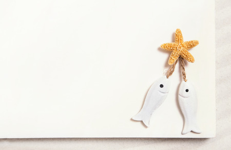 Two white fishes with starfish on a white summer background for religion, love or wedding items.の写真素材