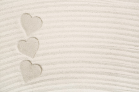 Three heart prints in the sand for a love background.の写真素材