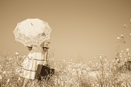 Old photo in sepia color. Girl with her umbrella walking alone and searching her way.の写真素材